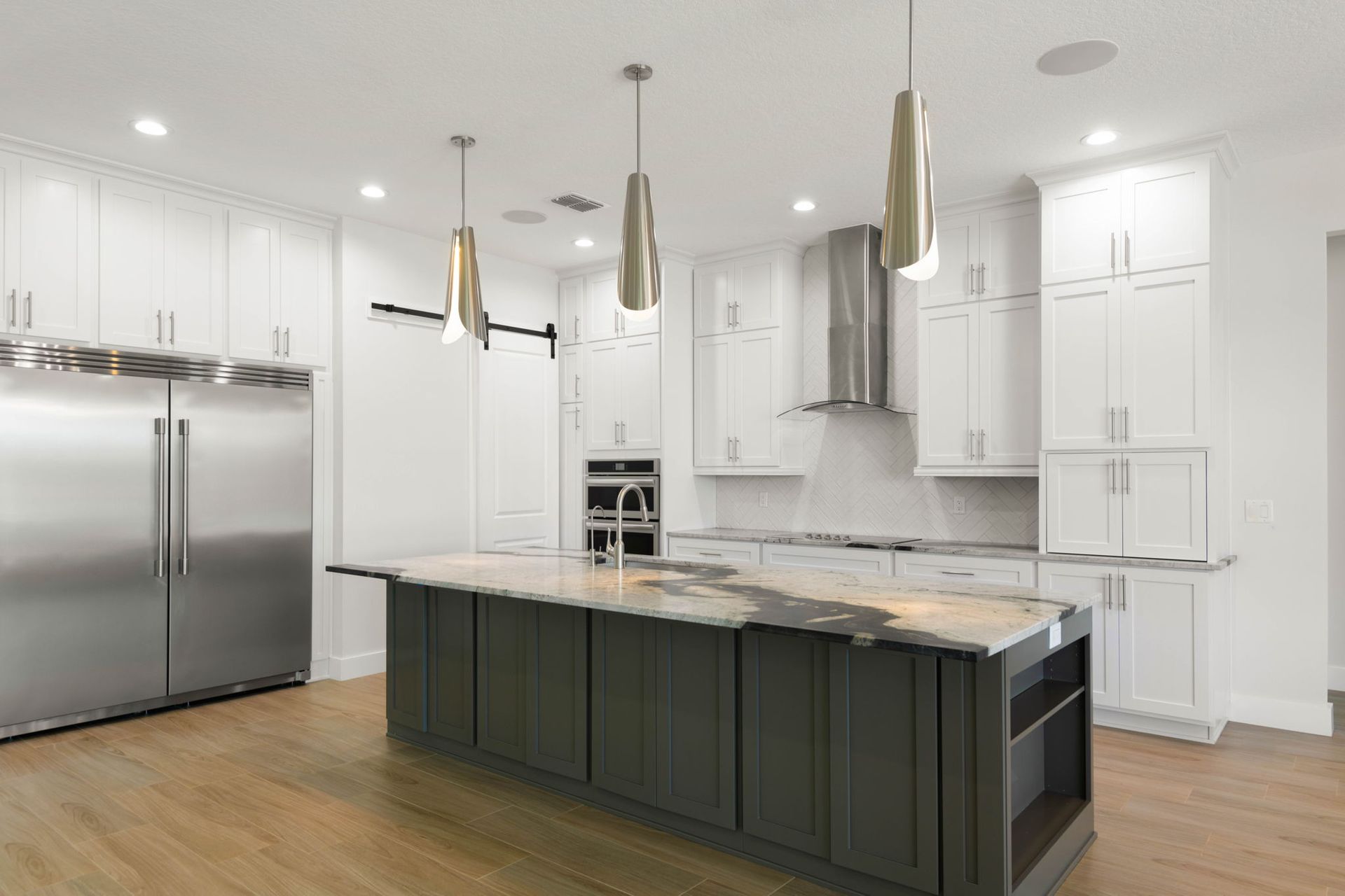 Modern kitchen with white cabinets, stainless steel appliances, and a gray island with pendant lights.