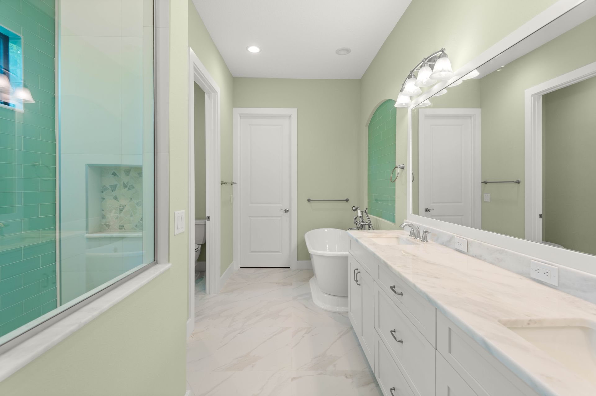 Elegant bathroom with a clawfoot tub, chandelier, and a window overlooking greenery.