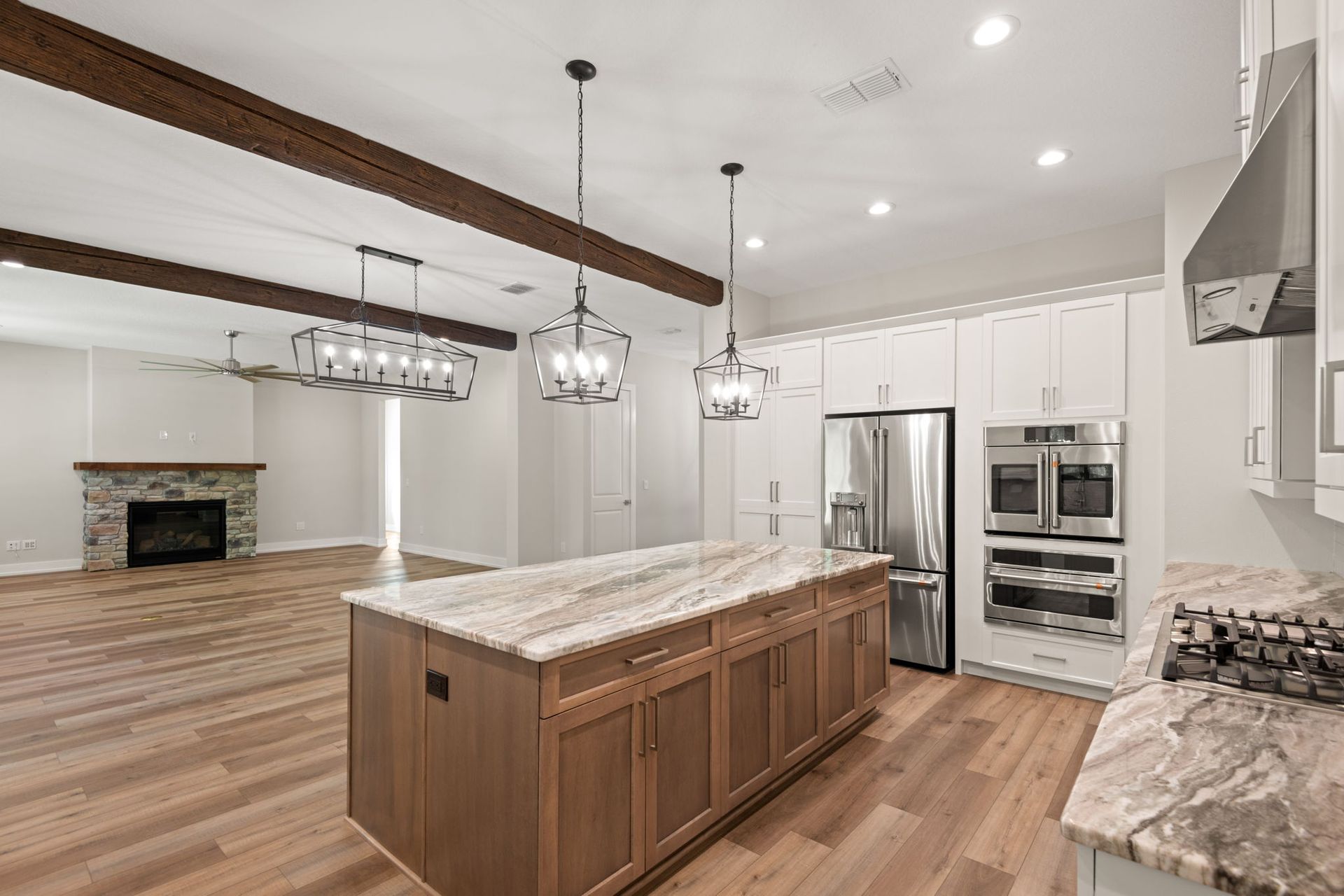 Spacious kitchen with island, wood cabinets, stone countertops, stainless steel appliances, and fireplace.
