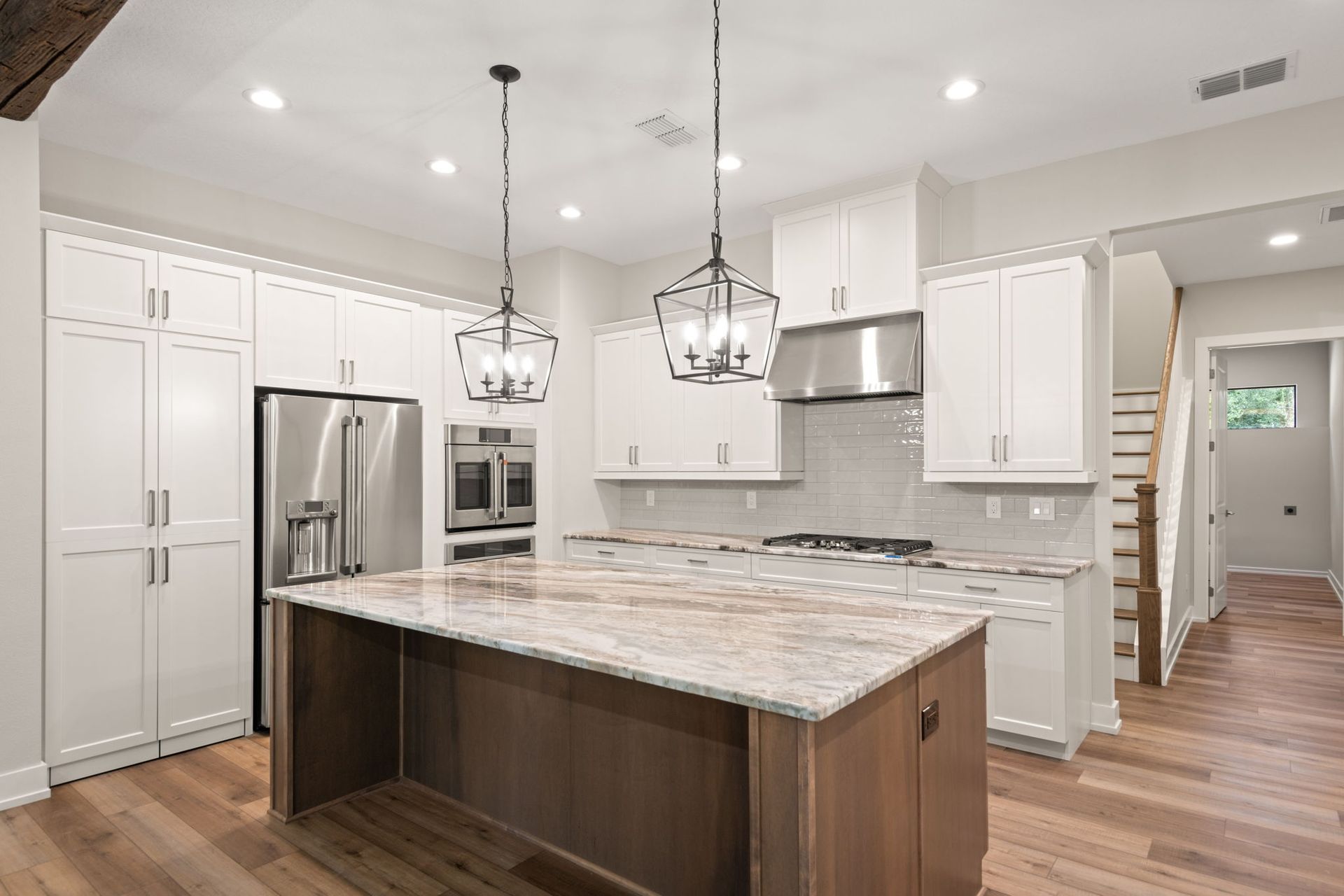 Modern kitchen with white cabinets, stainless steel appliances, and a brown island.