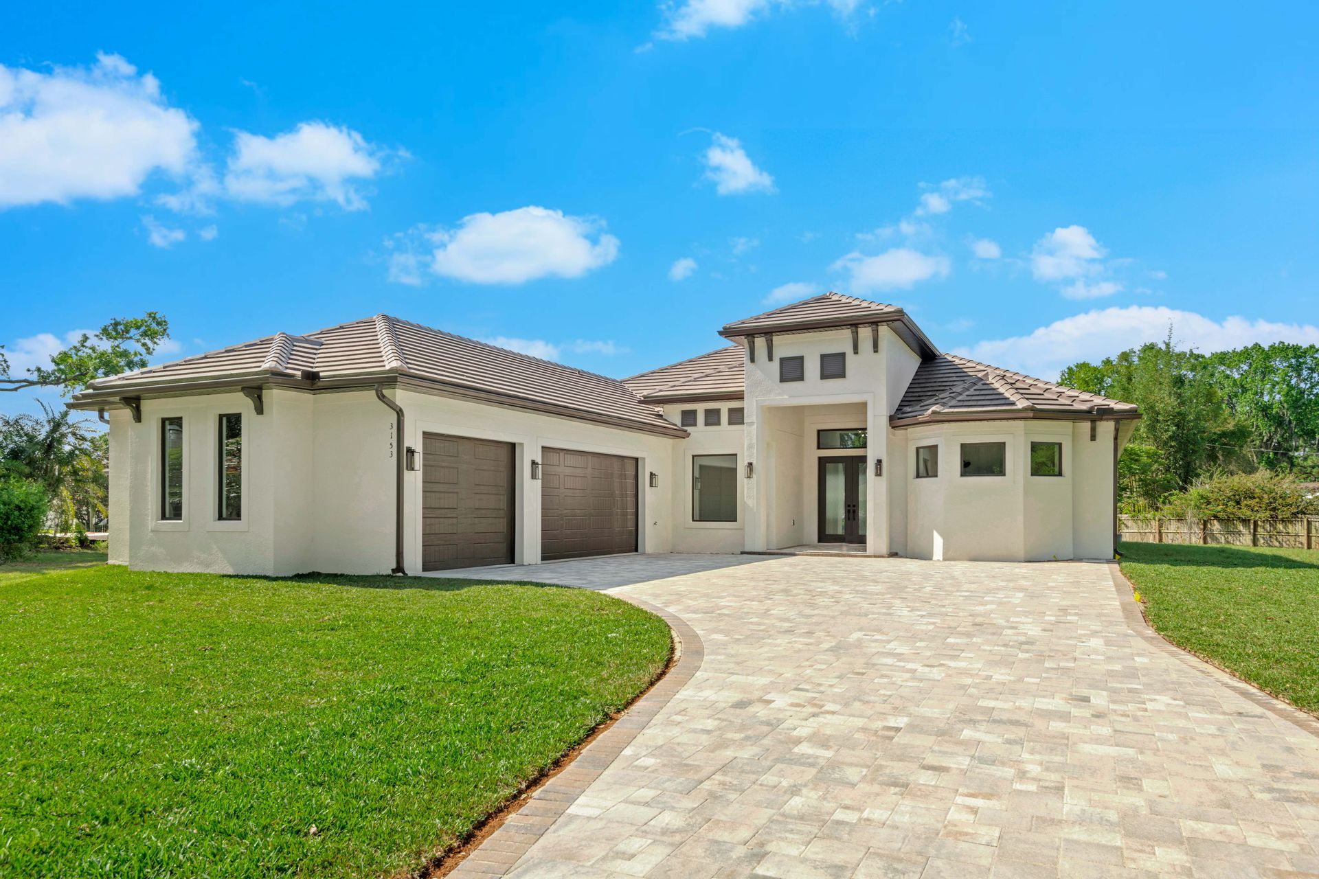 White farmhouse with a long porch, three dormers, and a green lawn under a colorful sunset.