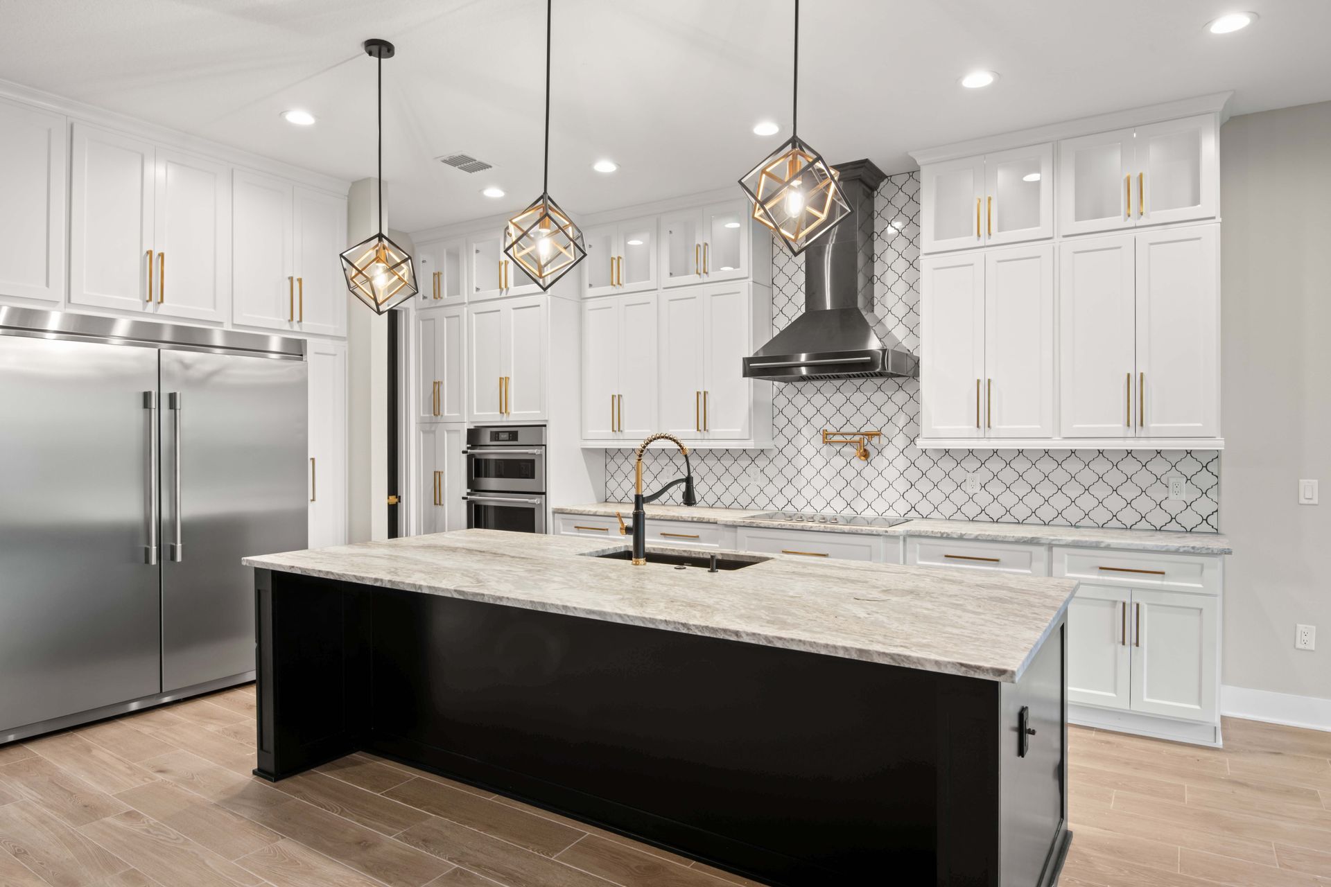 Modern kitchen with white cabinets, black island, and geometric pendant lights.