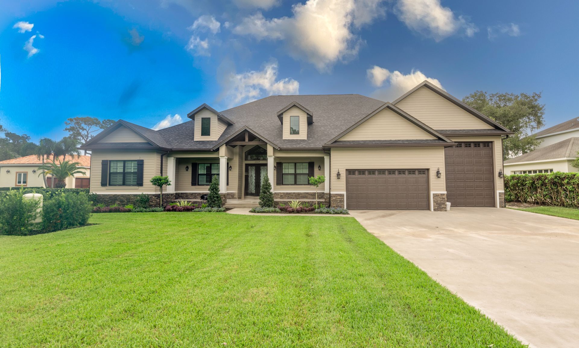 Beige single-story home with brown garage doors, green lawn, and blue sky.