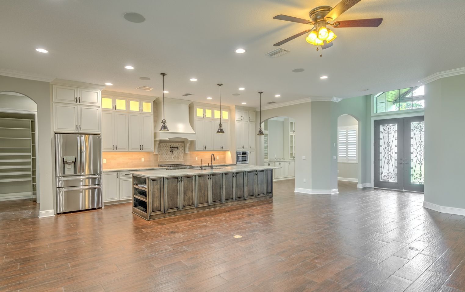 Spacious open-plan kitchen with island, stainless steel appliances, and wood floors.
