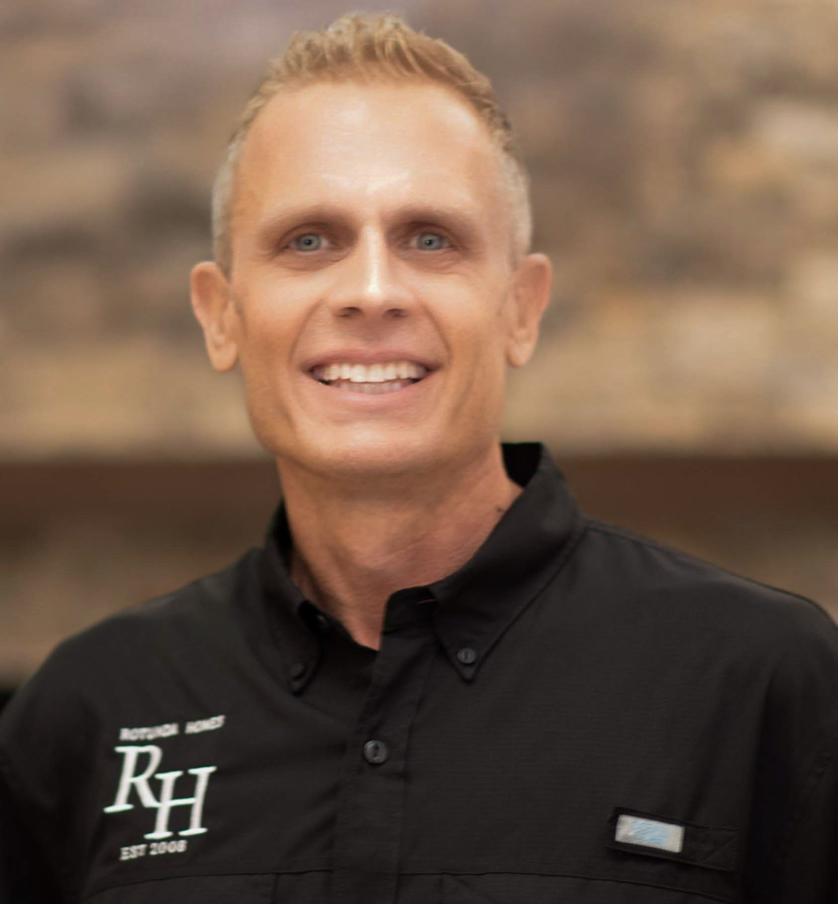 Smiling man in black shirt, logo