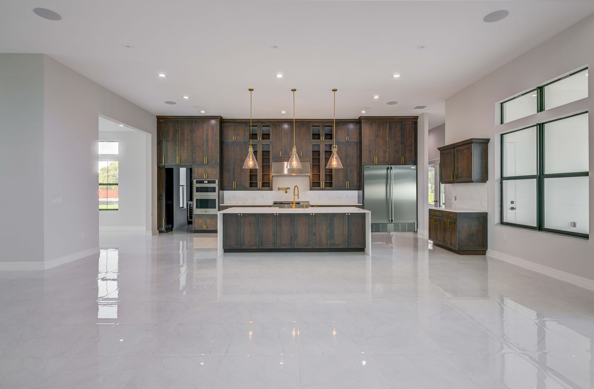Modern kitchen with dark wood cabinets, white countertops, and white tile floor.