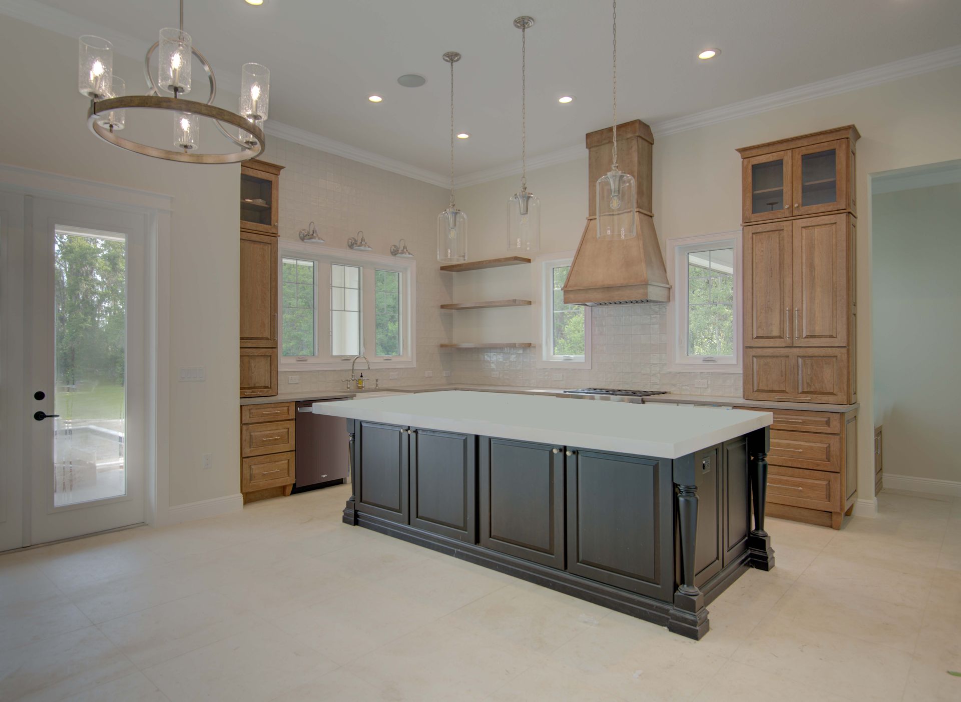 Spacious kitchen with dark island, wooden cabinets, and hanging light fixtures.