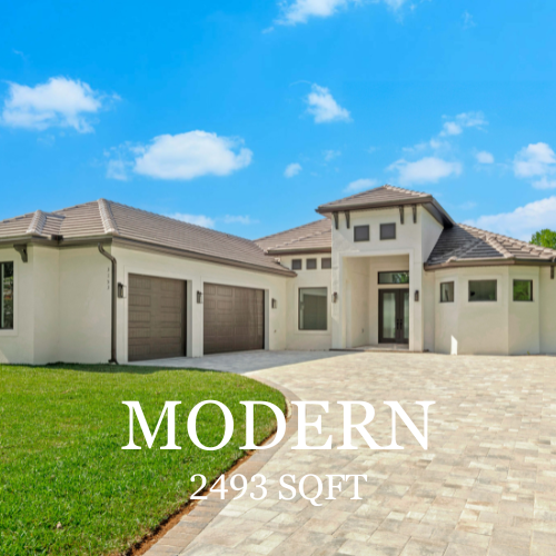 A modern, beige, single-story house with a two-car garage and a paved driveway under a blue, cloudy sky.