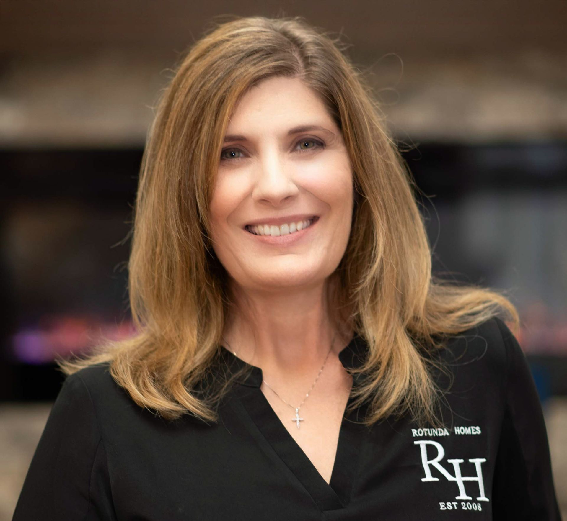 Woman with blonde hair smiling, wearing a black shirt with