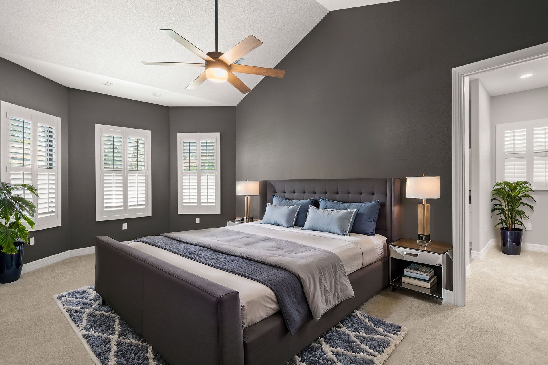 Bedroom with gray walls, a dark bed, and white shutters.