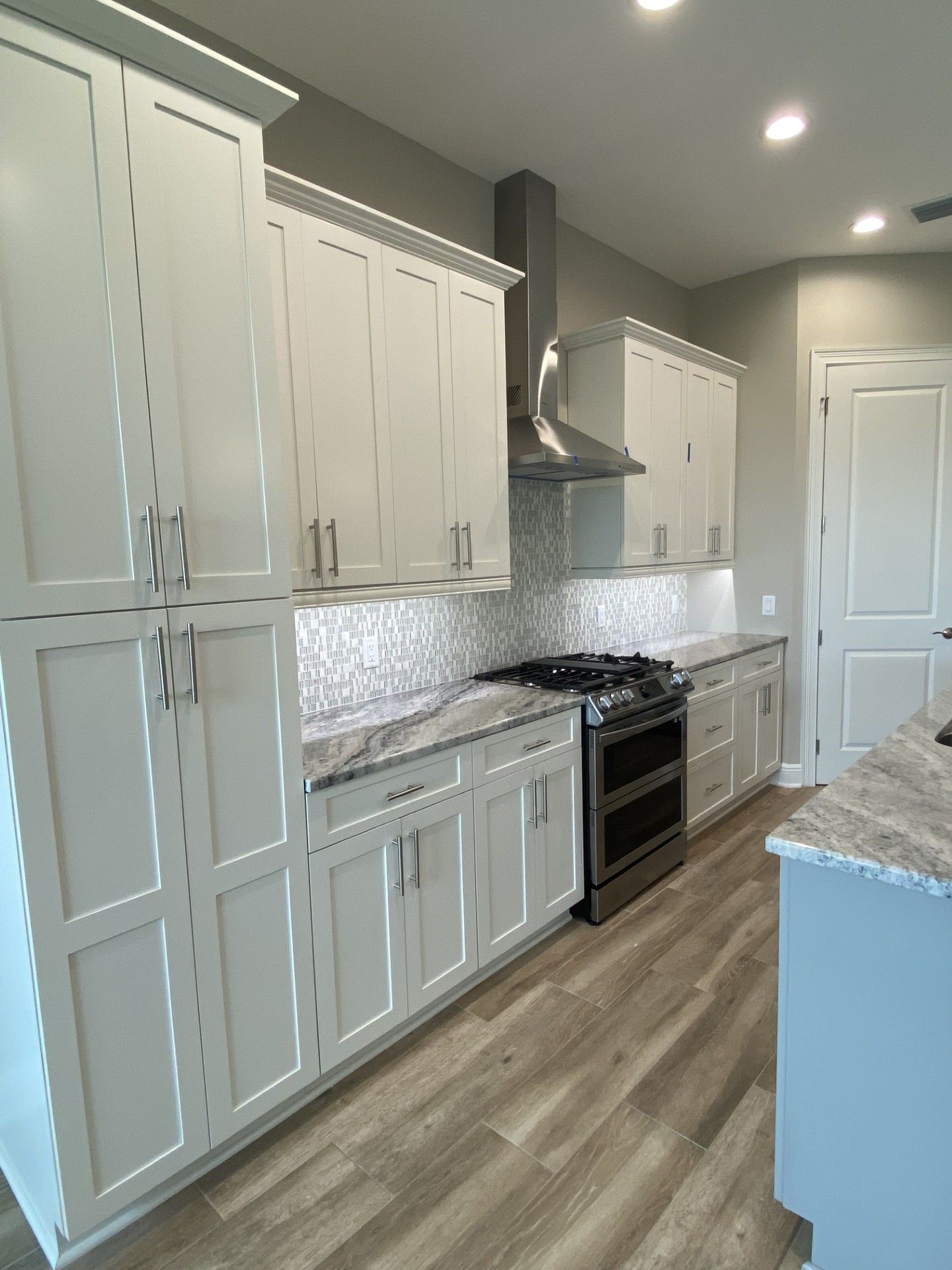 Open-concept kitchen and living area with black island, white cabinets, and large glass doors leading to a pool.