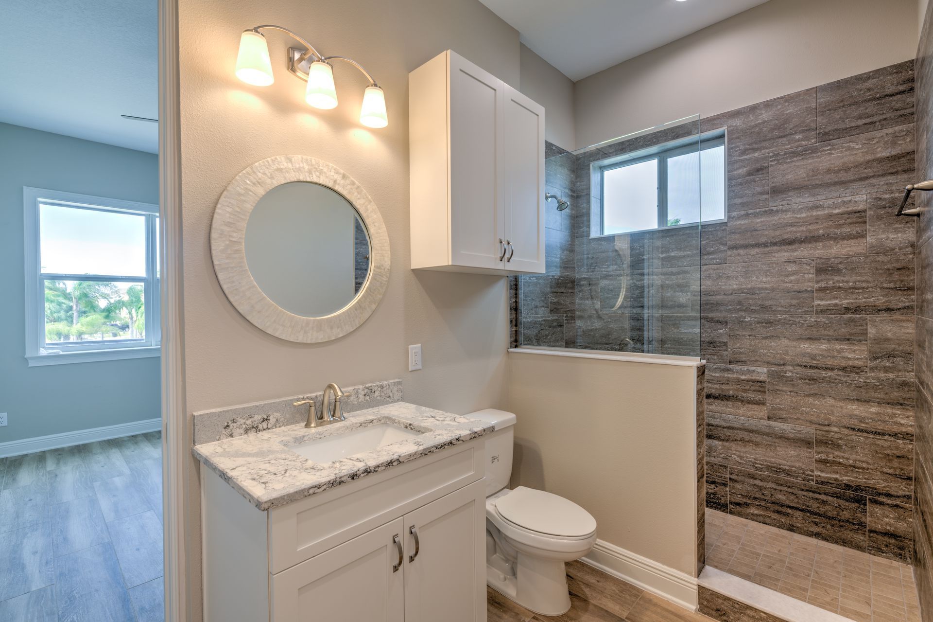 Spacious kitchen with island, pendant lights, large windows overlooking a backyard and a fireplace on a black wall.