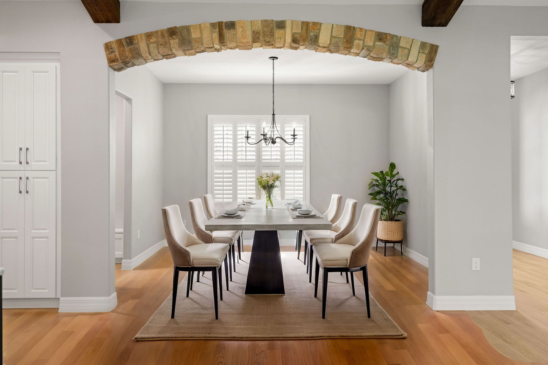 Formal dining room with a long table, chairs, and a stone archway.