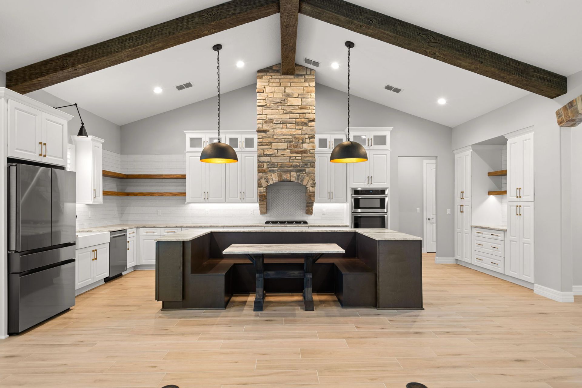 Modern kitchen with white cabinets, stone chimney, and brown dining nook.