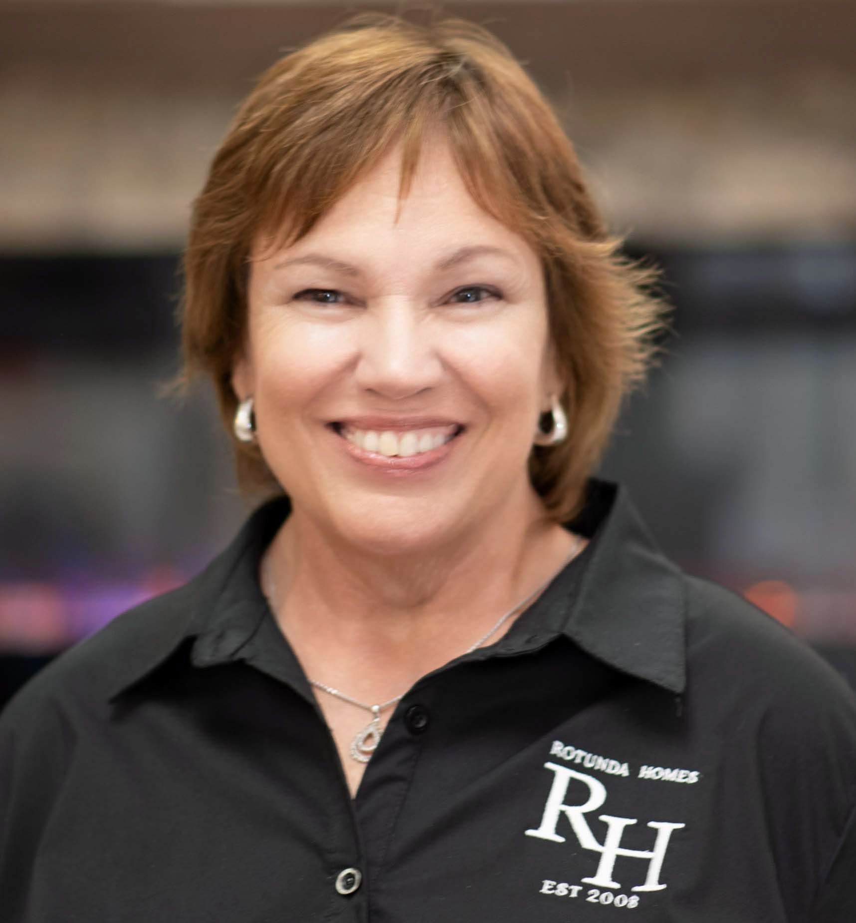 Woman with short brown hair smiling, wearing a black shirt with