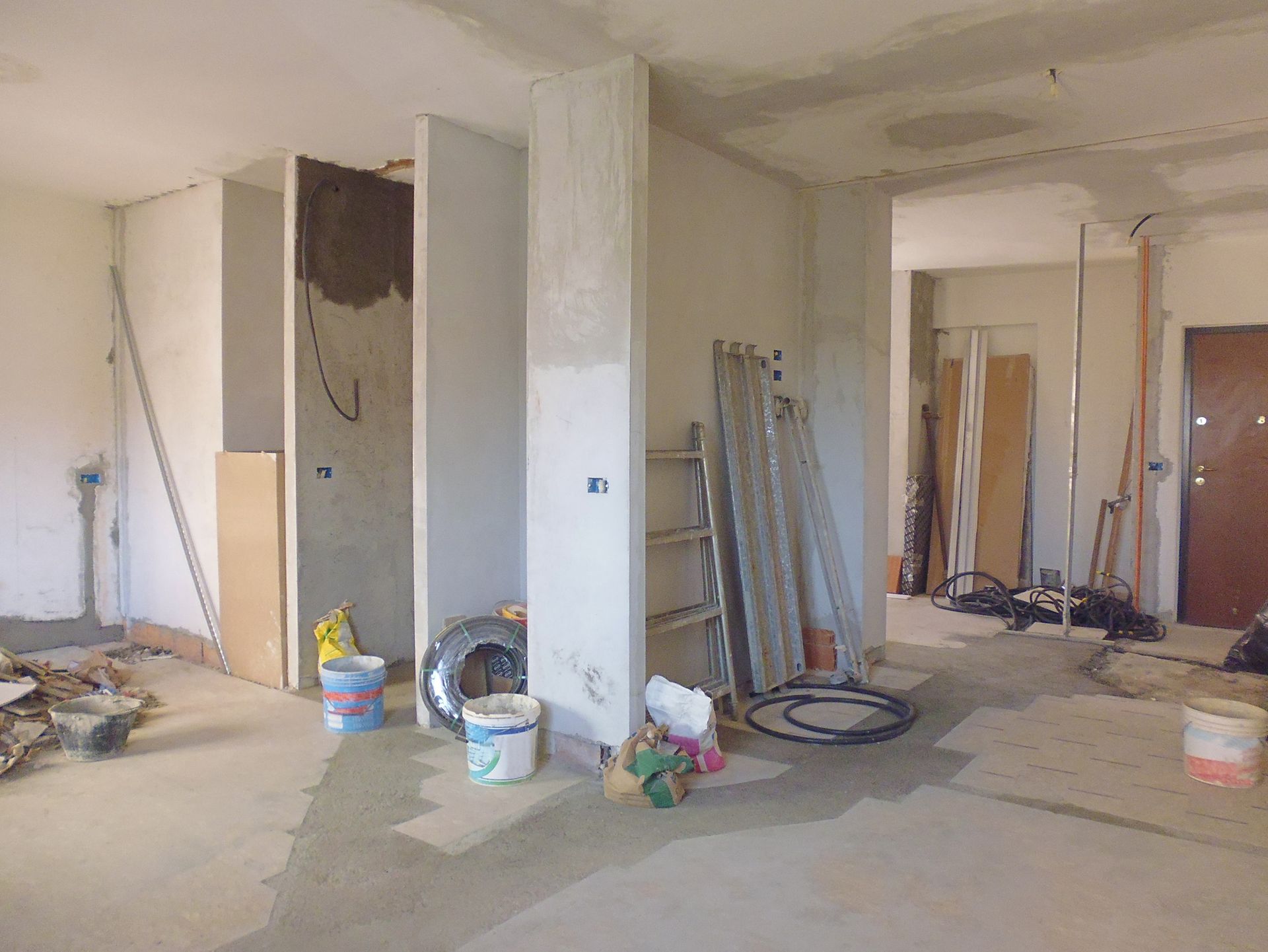 Stanza in costruzione con pareti non rifinite, cavi elettrici e materiali da costruzione scoperti.