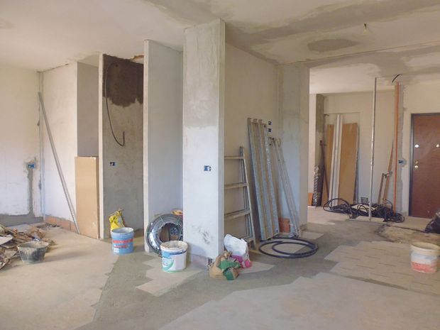 Stanza in costruzione con pareti non rifinite, cavi elettrici e materiali da costruzione scoperti.