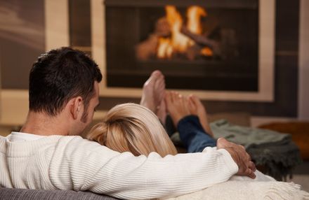 couple cuddling on couch in front of fireplace