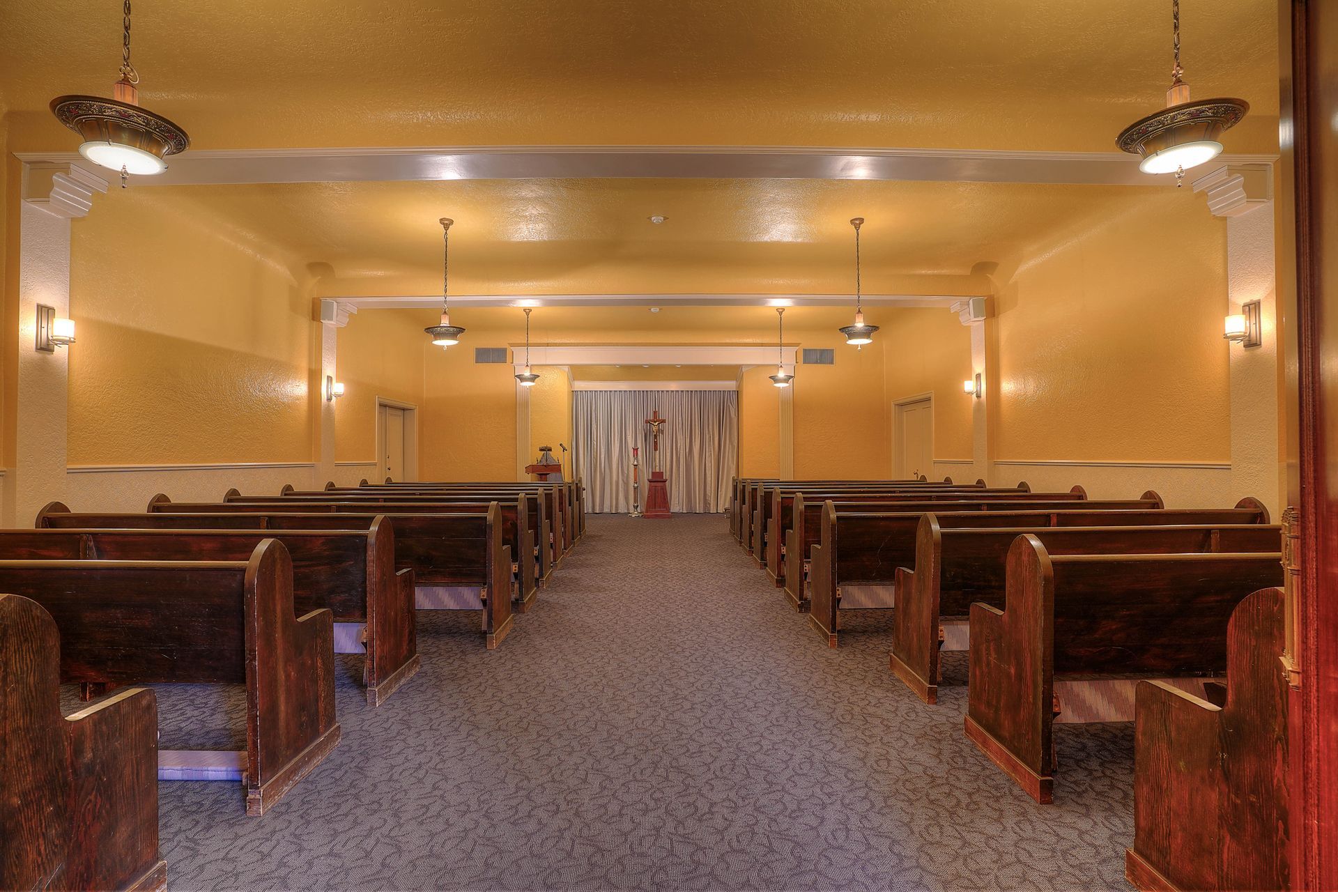 A church with rows of wooden benches and a carpeted floor.