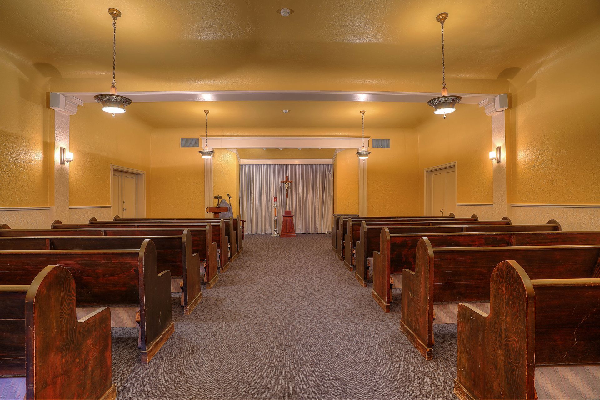 An empty church with wooden benches and a cross on the wall