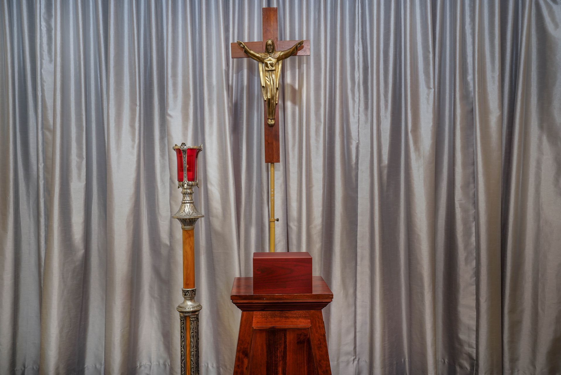 A crucifix is sitting in front of a white curtain in a church.