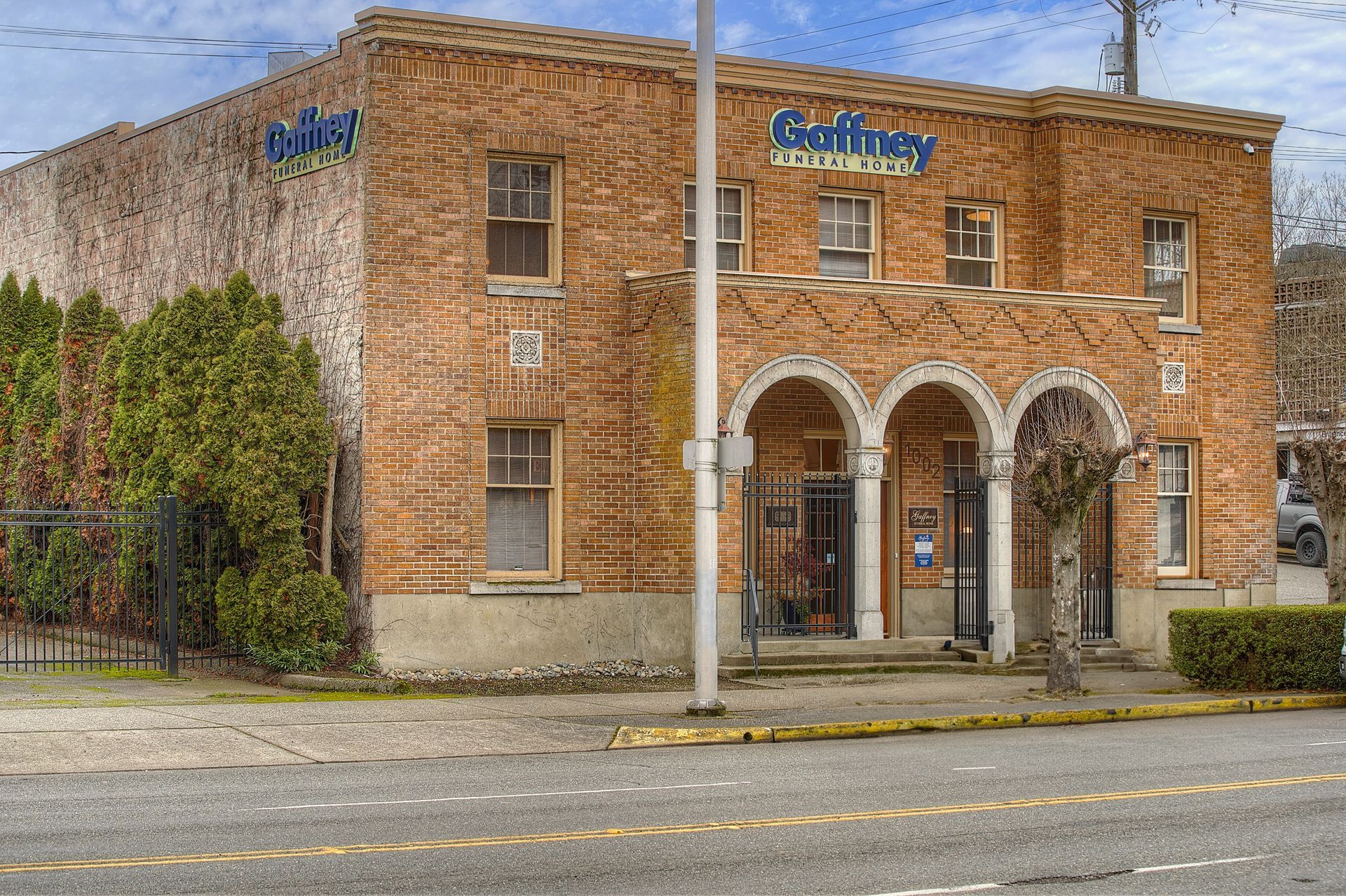 A large brick building with a porch and trees in front of it