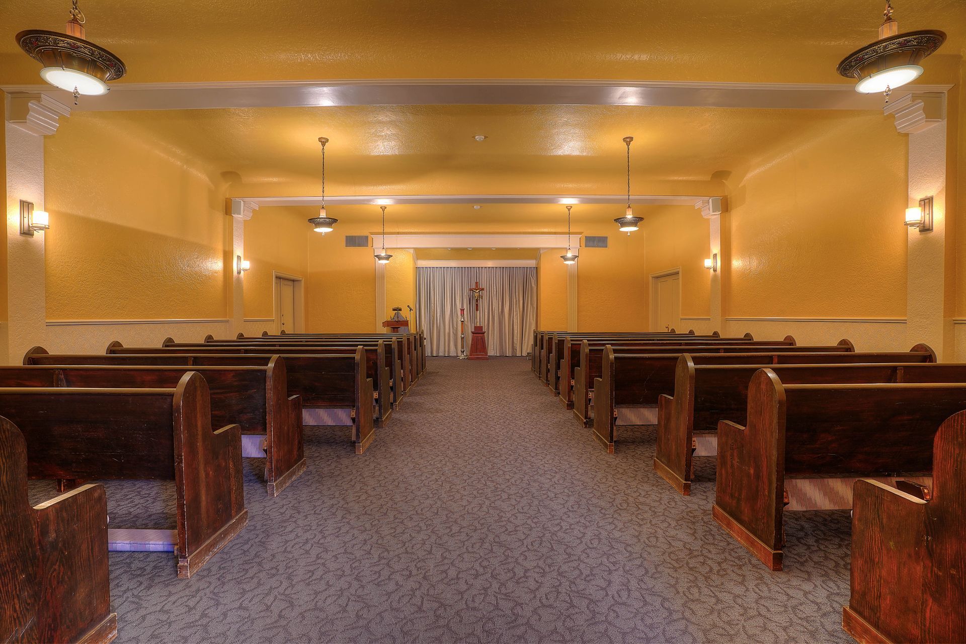 A church with rows of wooden benches and a carpeted floor.
