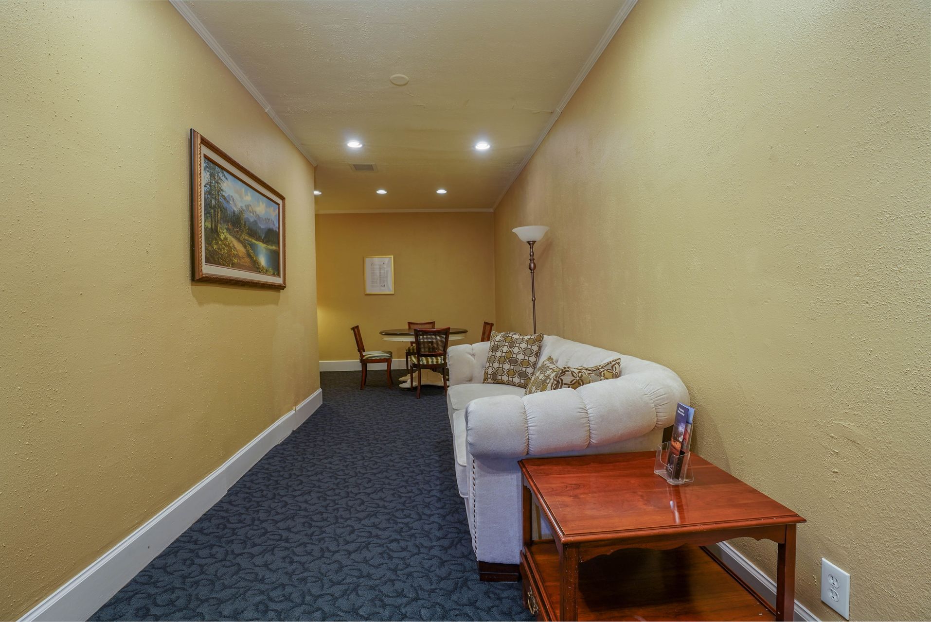 A long hallway with a couch , table and chairs.