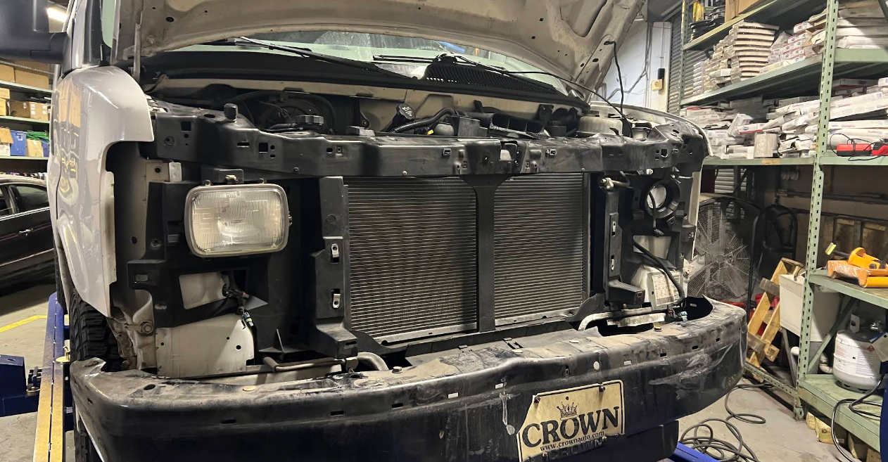 A truck is being repaired in a garage with the hood open.