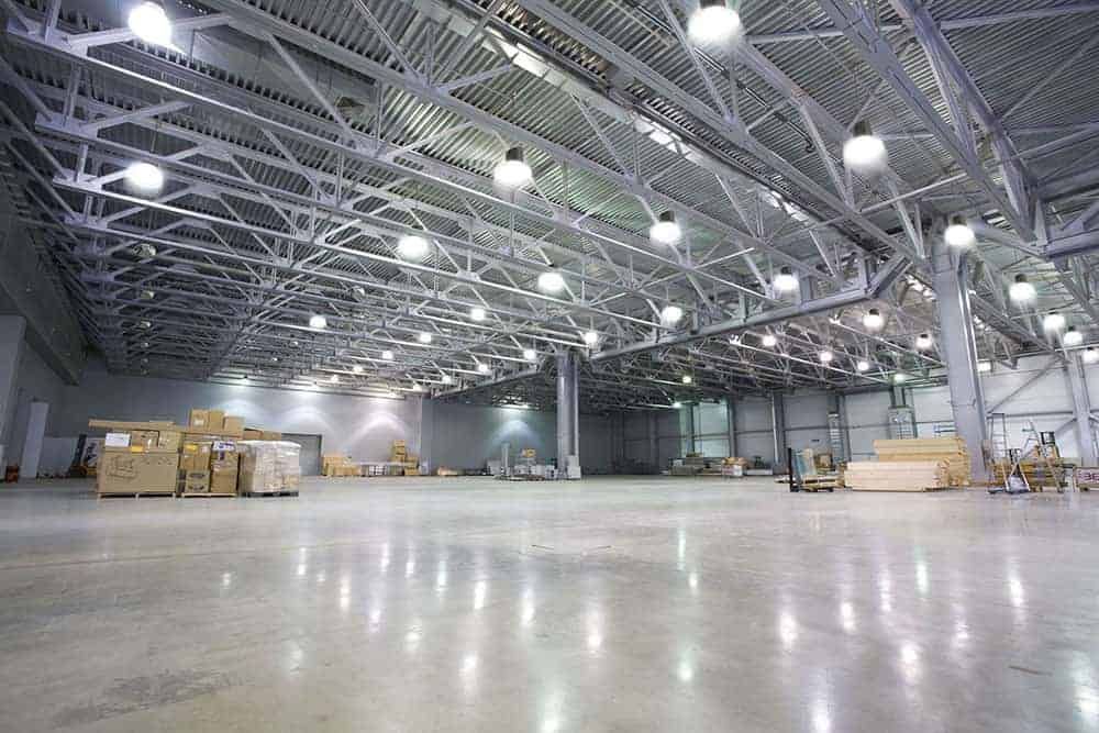 A large empty warehouse with lots of lights on the ceiling.