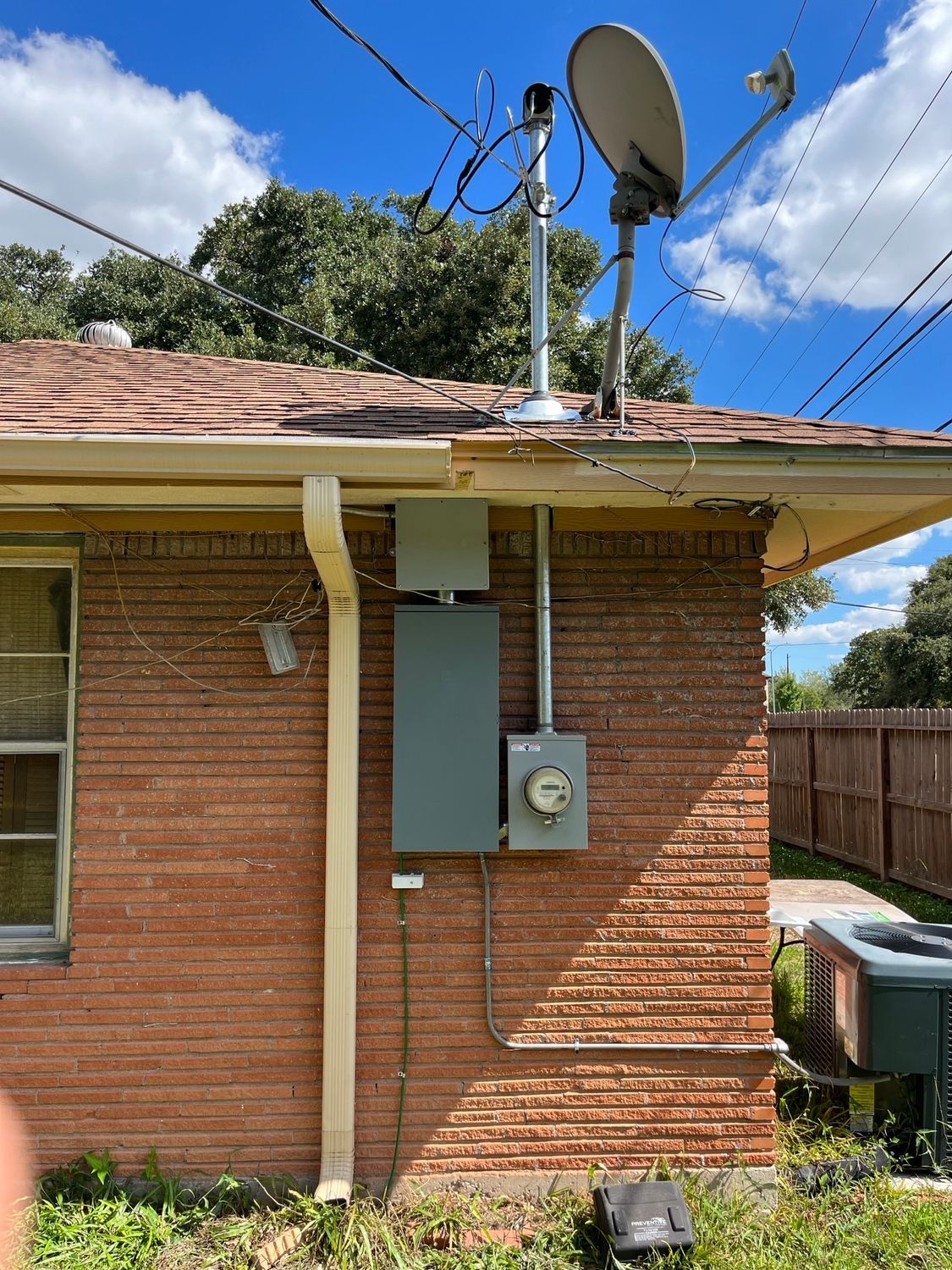 A brick house with a satellite dish on the roof.
