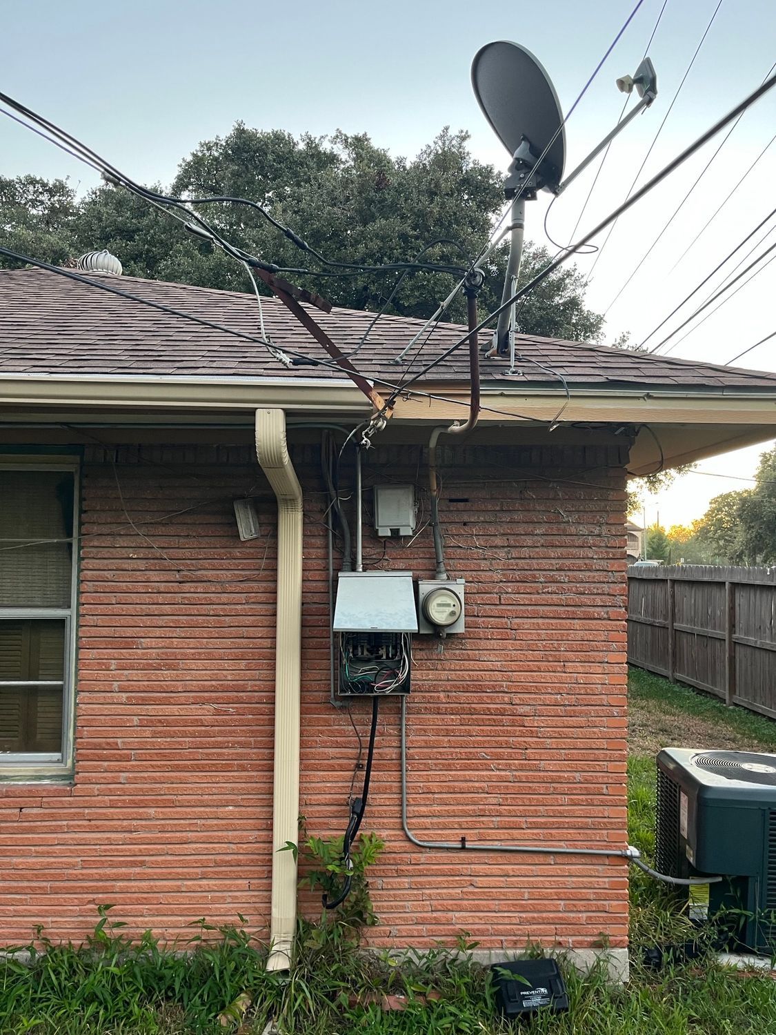 A brick house with a satellite dish on the roof.