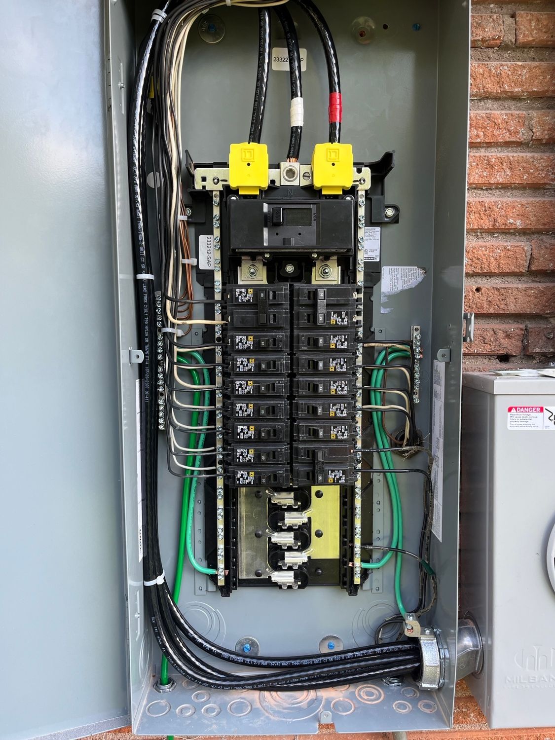 A close up of a electrical panel with a brick wall in the background.