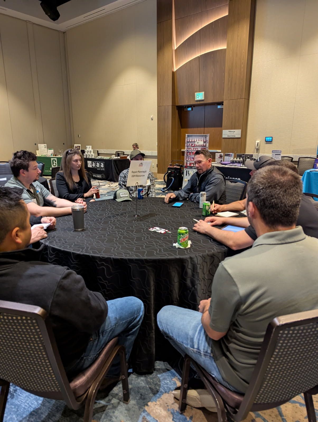 People seated around a black table playing cards. Conference room setting.
