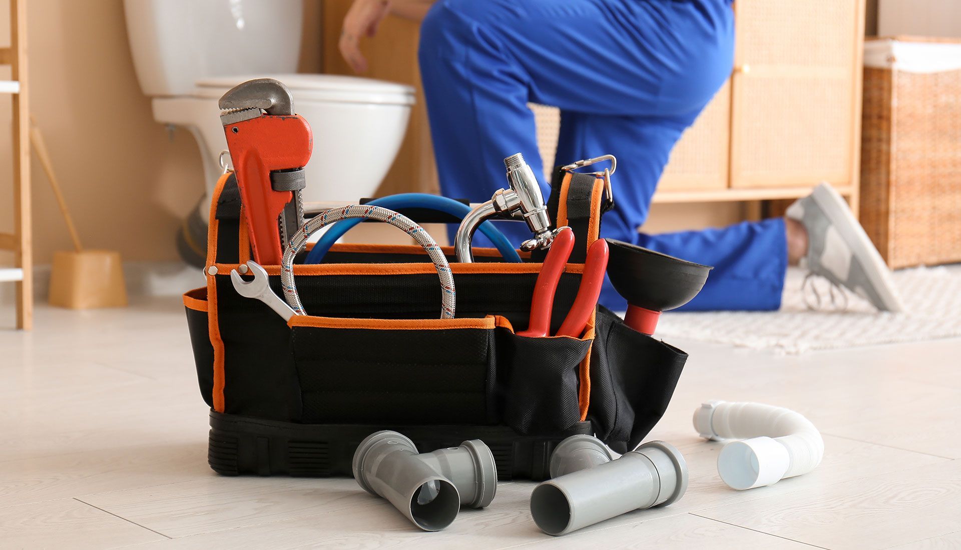 Tool bag with pipes and plumber tools in bathroom, closeup