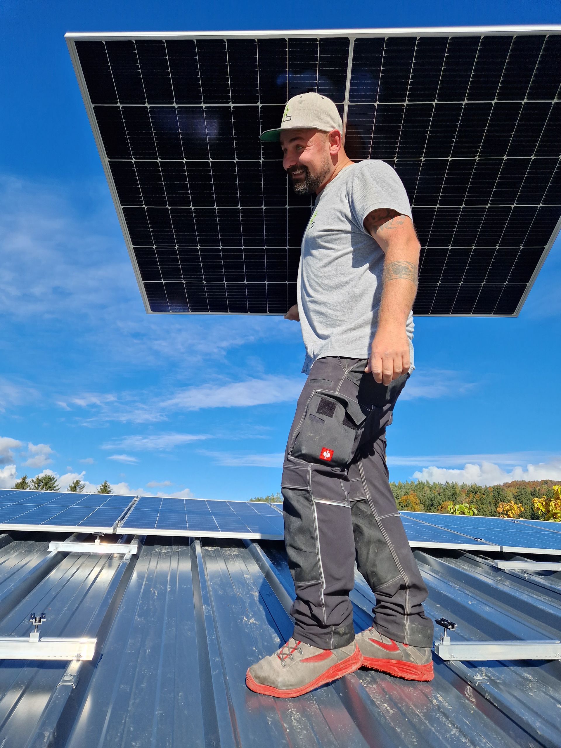 ein Mann steht auf einem Dach und hält ein Solarpanel in der Hand