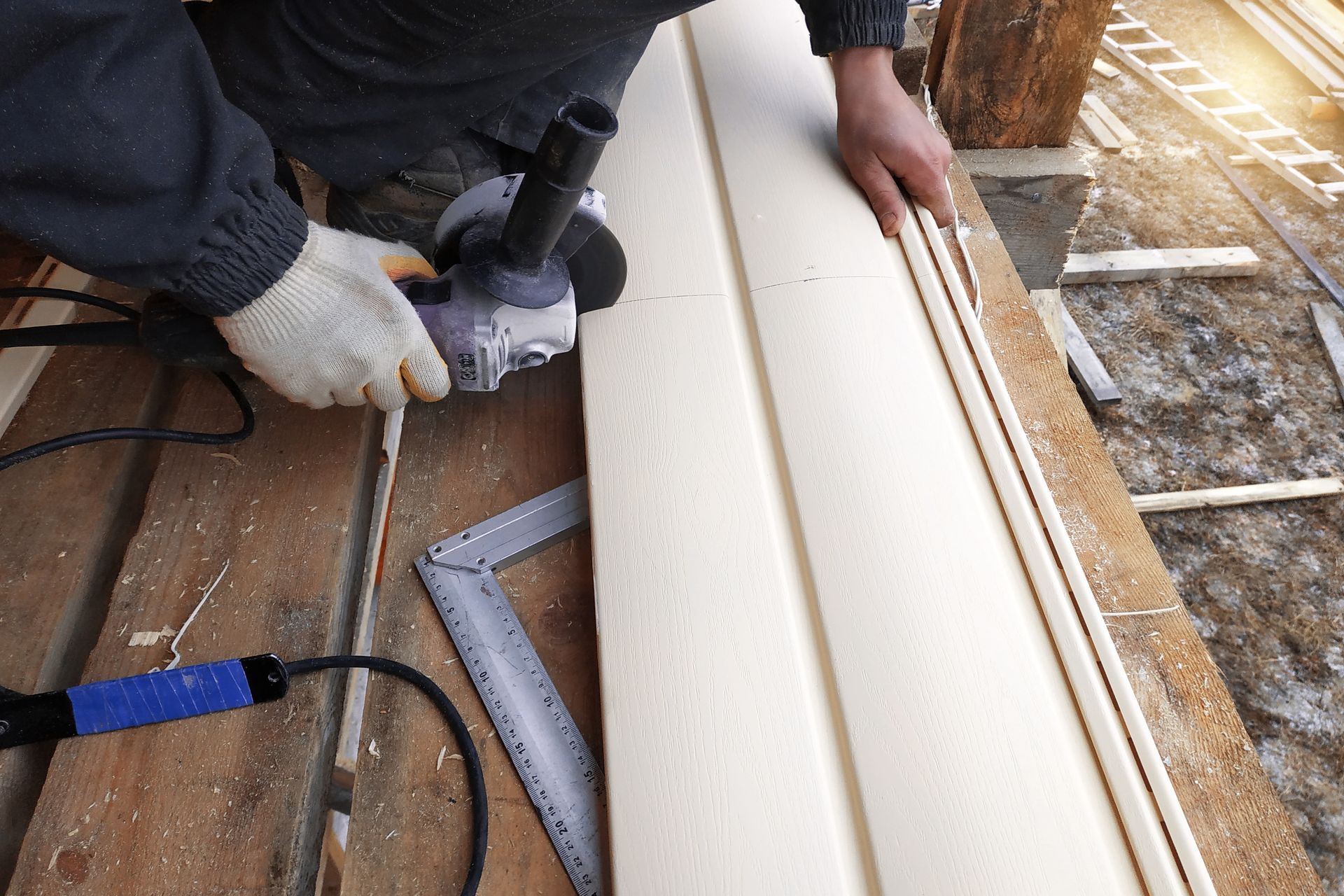 Person using a power grinder to cut siding on a wooden structure, outdoors.