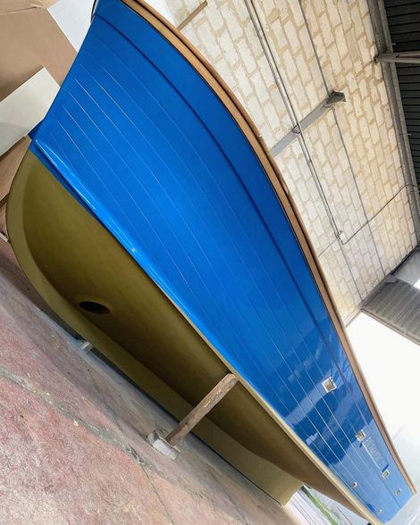 Una veduta grandangolare dello scafo di una barca in vetroresina in costruzione, che mostra la sua struttura interna a griglia e l'intelaiatura di supporto.