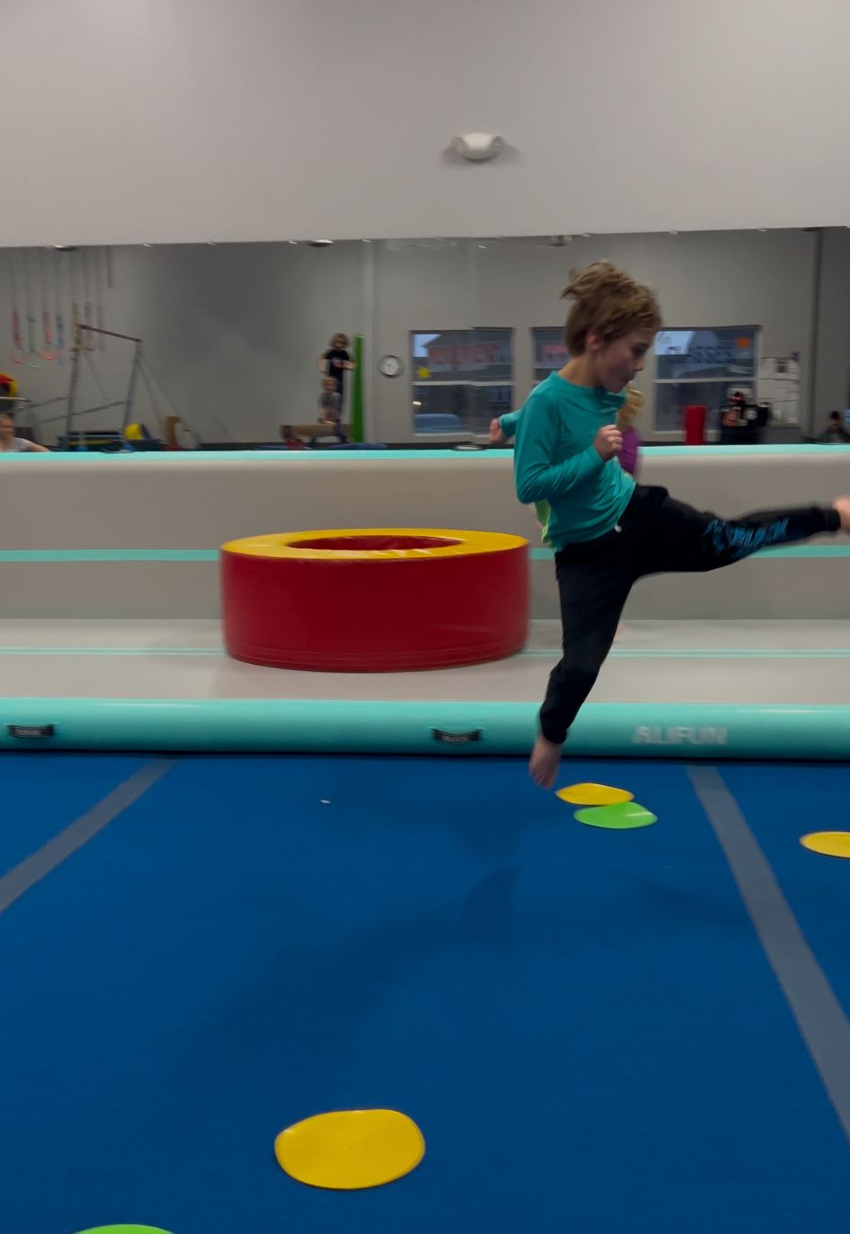 A young girl is doing a trick on a gymnastics mat
