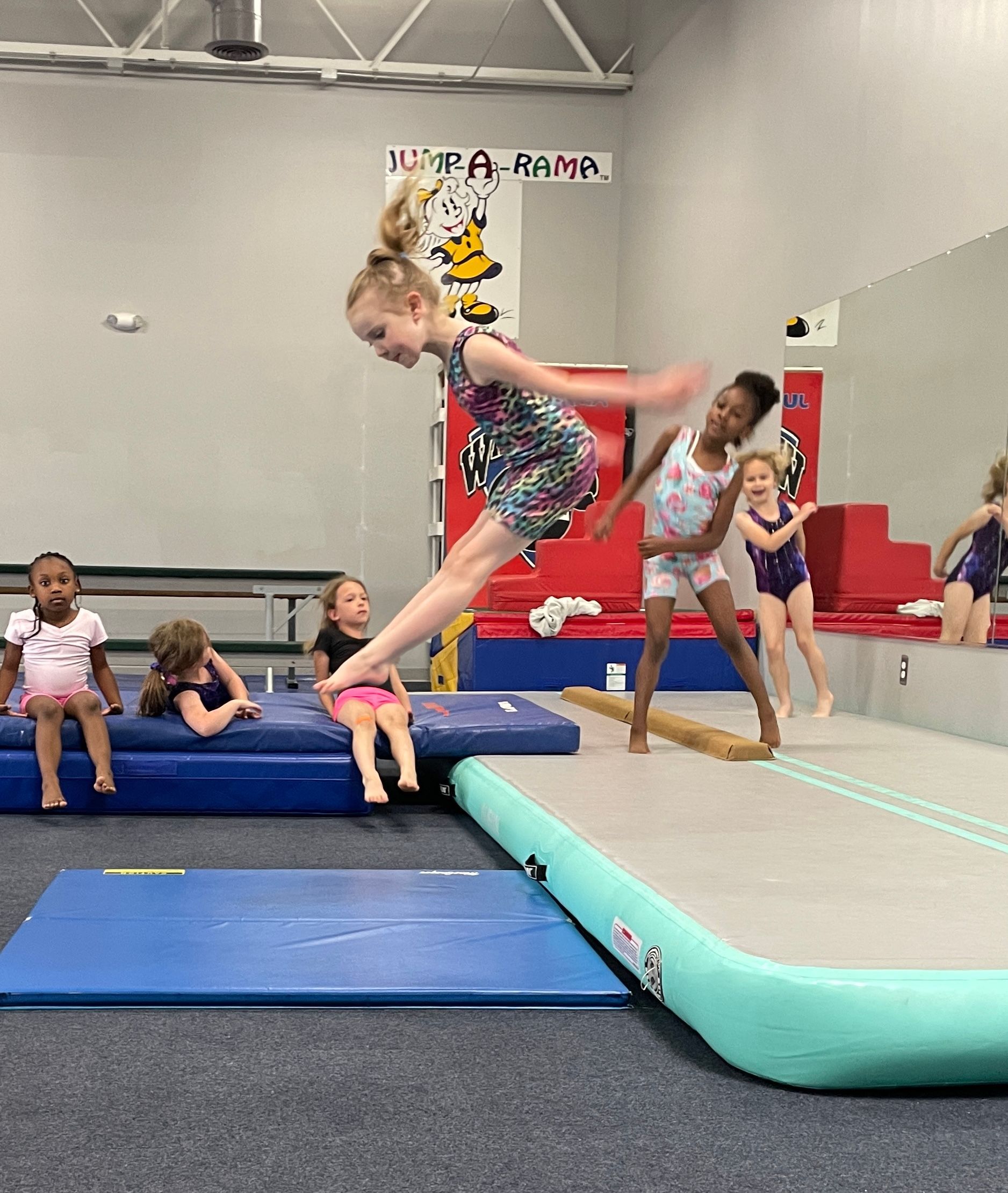 A group of young girls are practicing gymnastics in a gym.