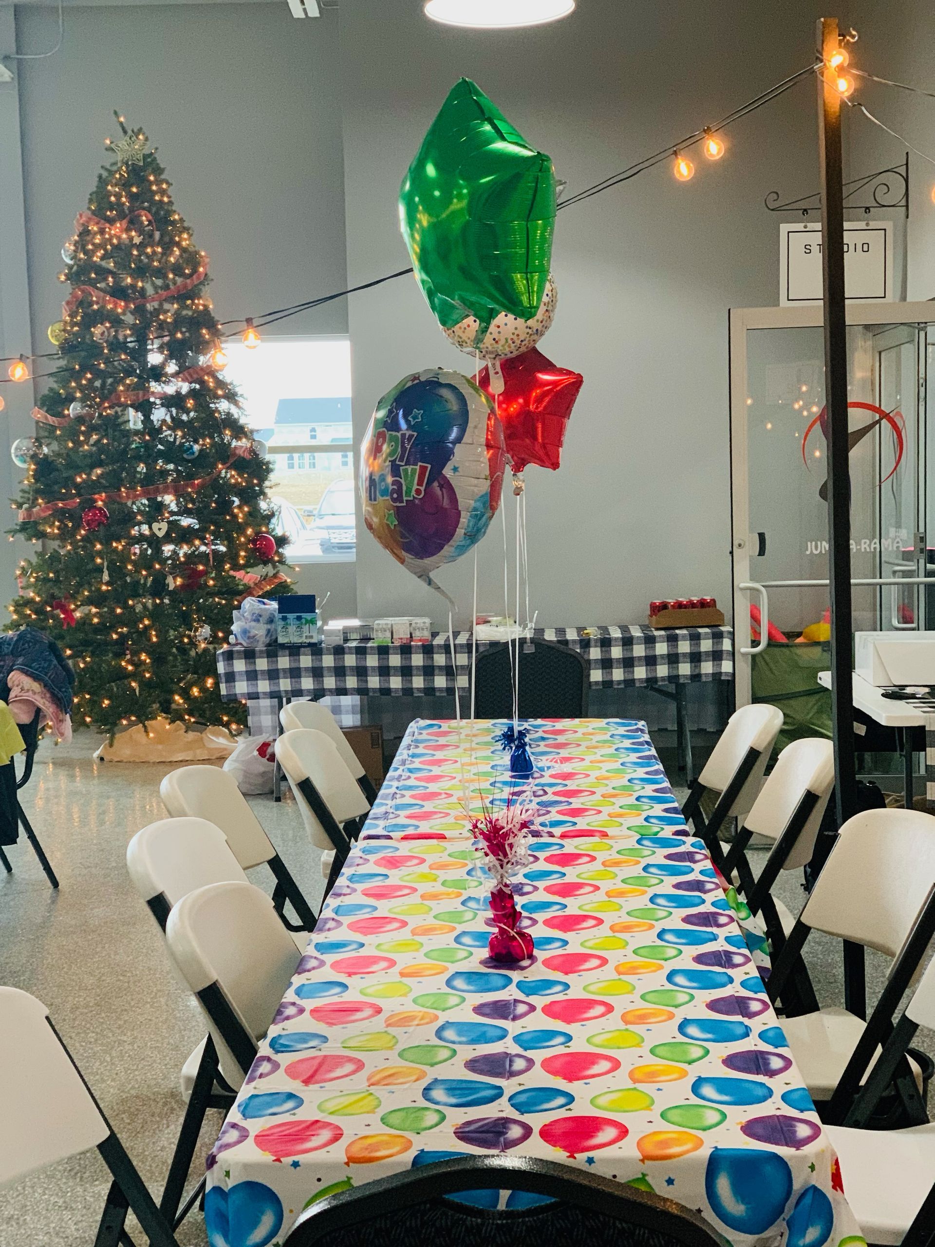 A long table with balloons on it and a christmas tree in the background.