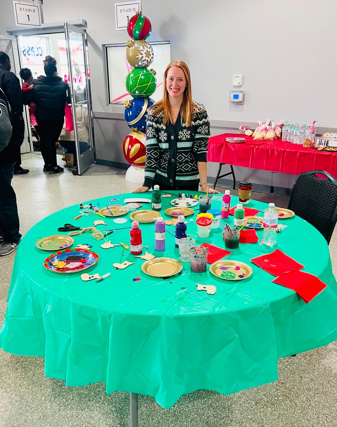 A woman is standing in front of a table with plates and balloons on it.