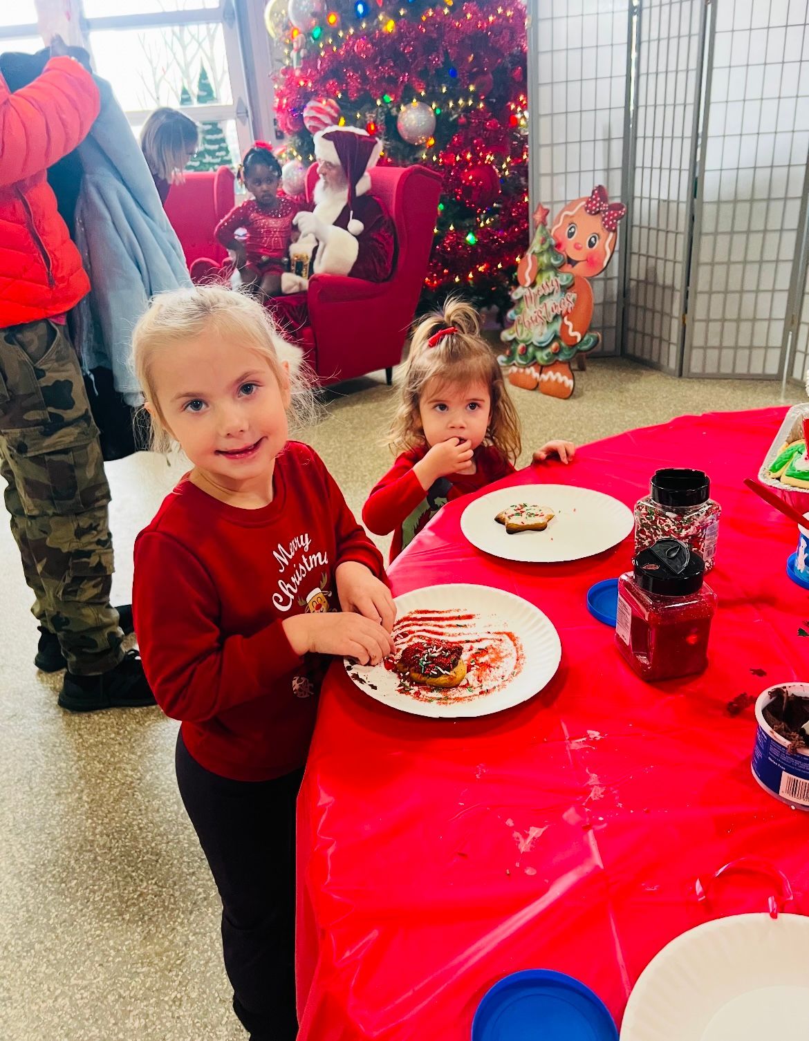 Two little girls are sitting at a table with plates of food.