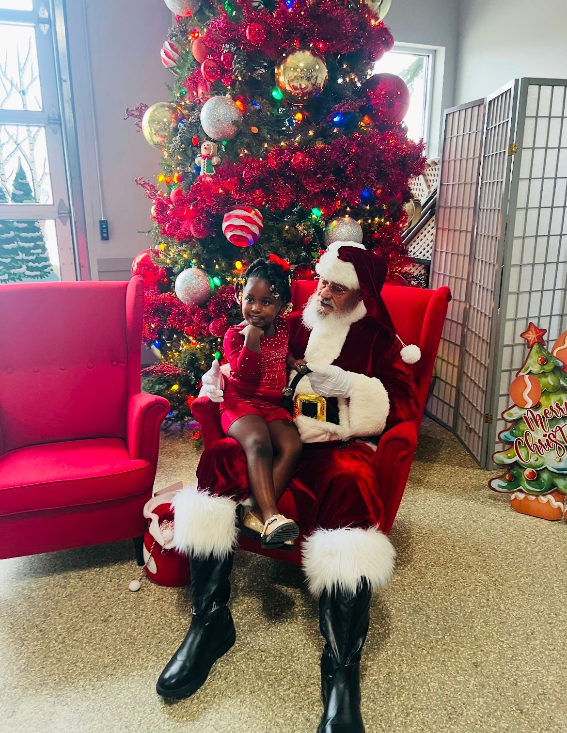 A little girl is sitting on santa 's lap in front of a christmas tree.