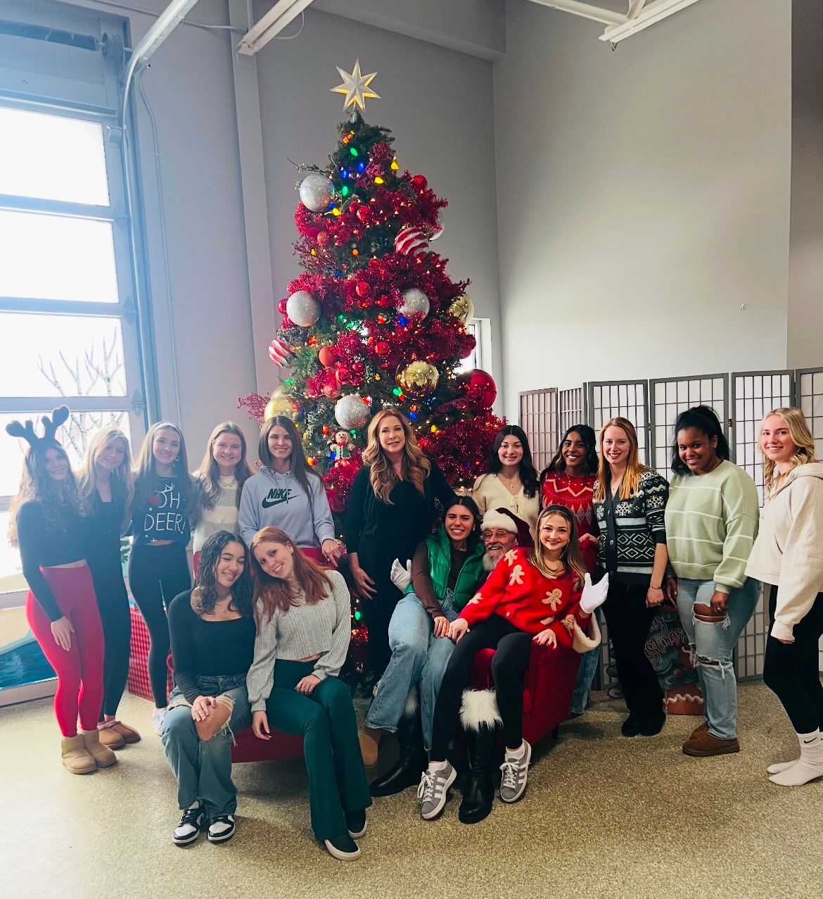 A group of people are posing for a picture in front of a christmas tree.