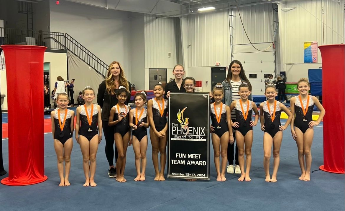 A group of young girls are posing for a picture in a gym.