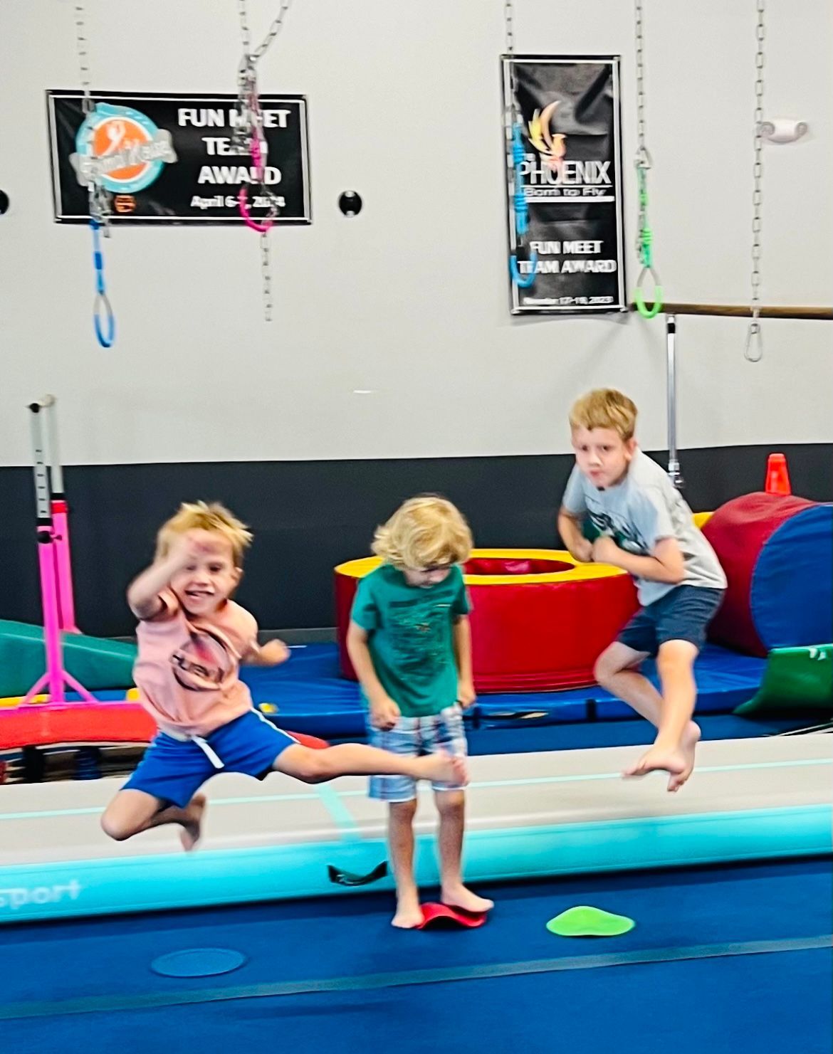 A group of young children are jumping on a balance beam in a gym.