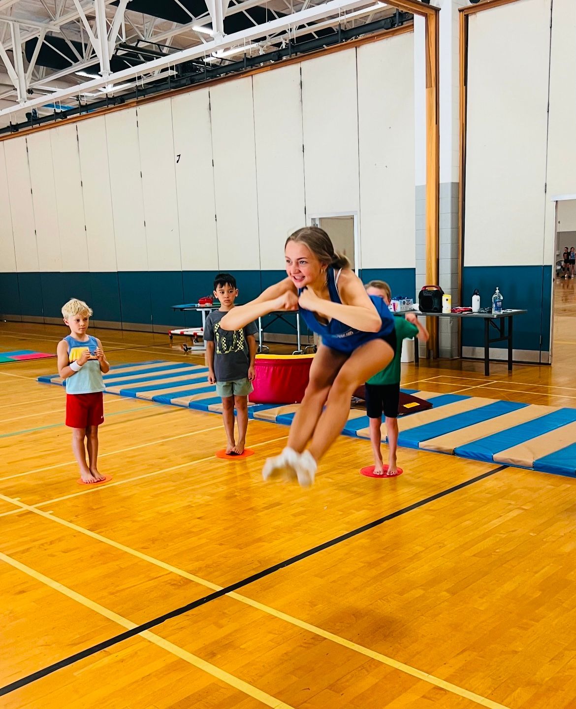 A girl is jumping in the air on a gym floor