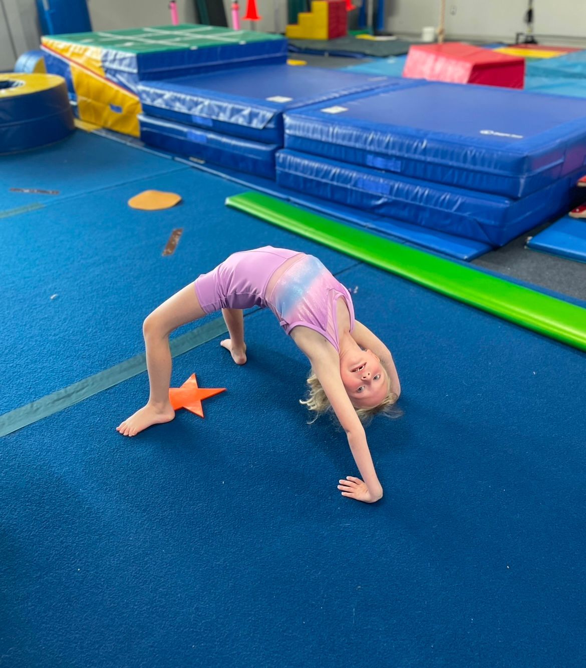 A little girl is doing a handstand in a gym