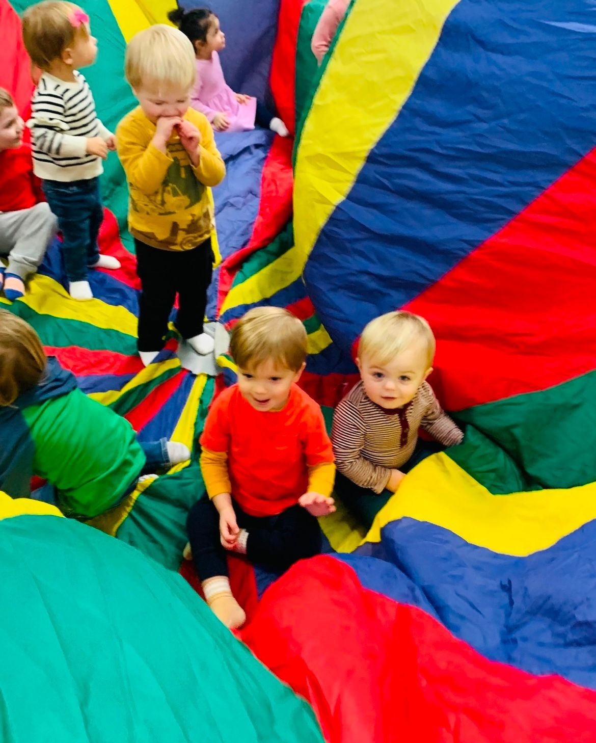 A group of children are playing with a colorful parachute